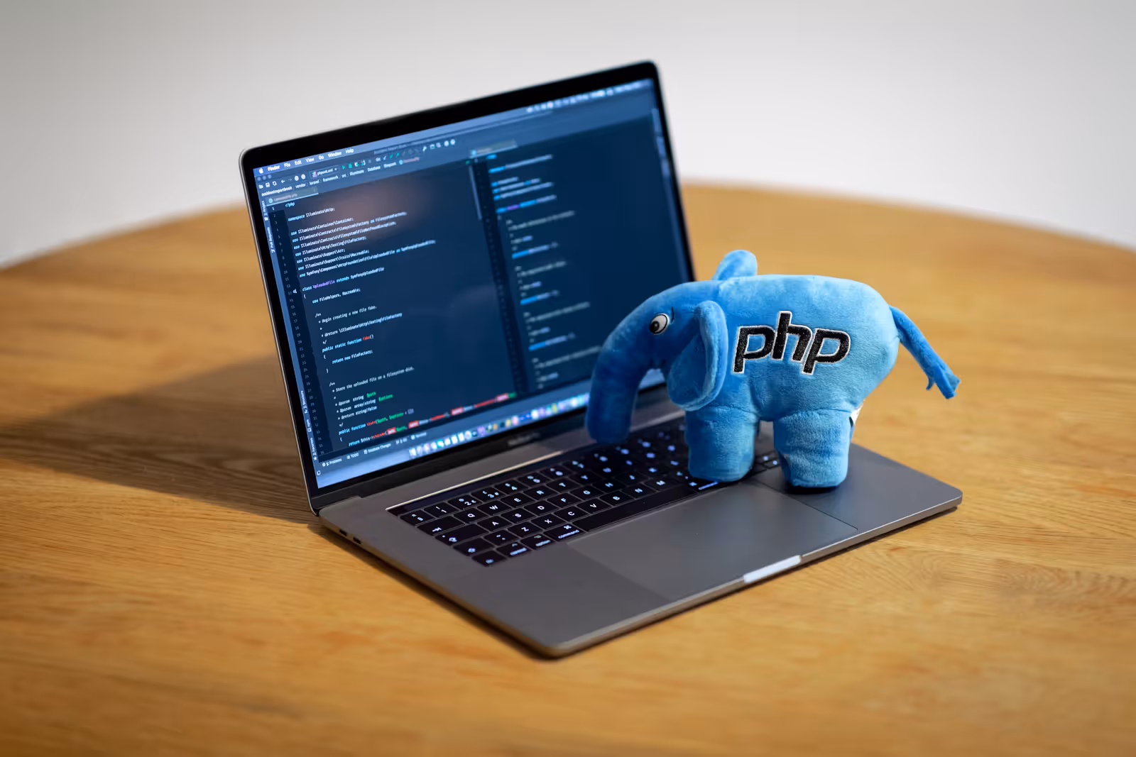 A laptop screen displaying colorful PHP source code in a dark-themed editor